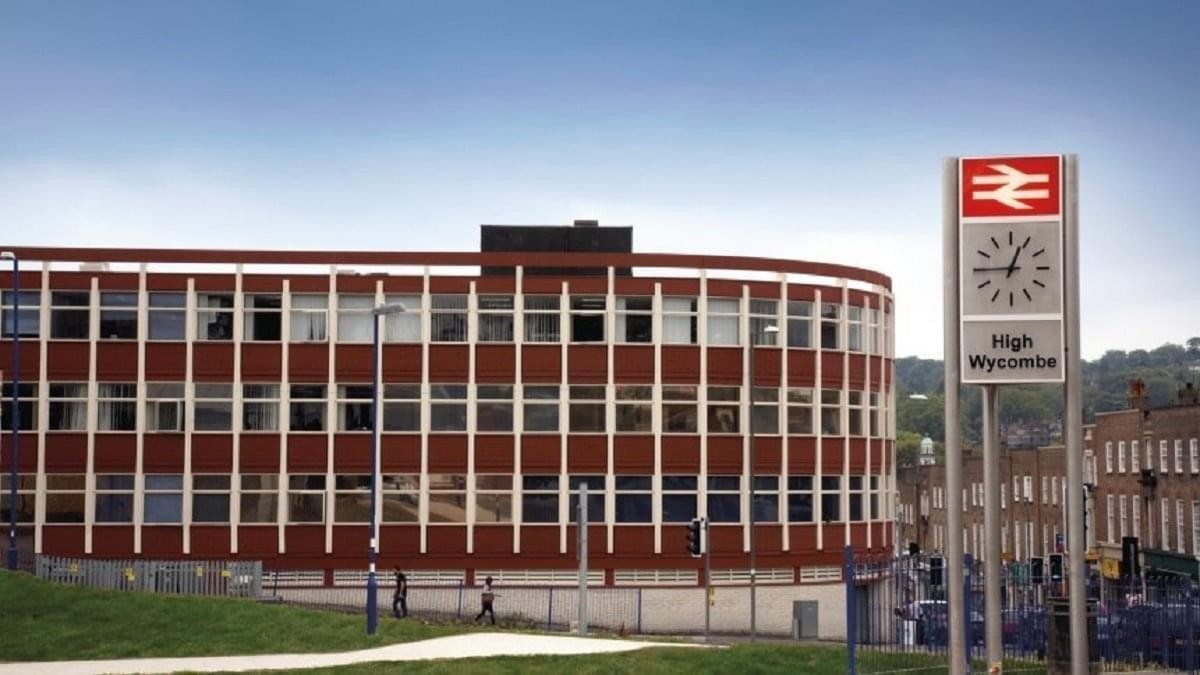Exterior view of the curved brick facade of Prospect House with a train station sign in the foreground.