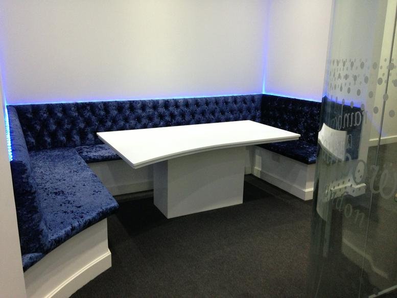 Plush blue velvet booth seating around a white meeting table at Rainbow House, 10-12 Lumina Way, Enfield Town.