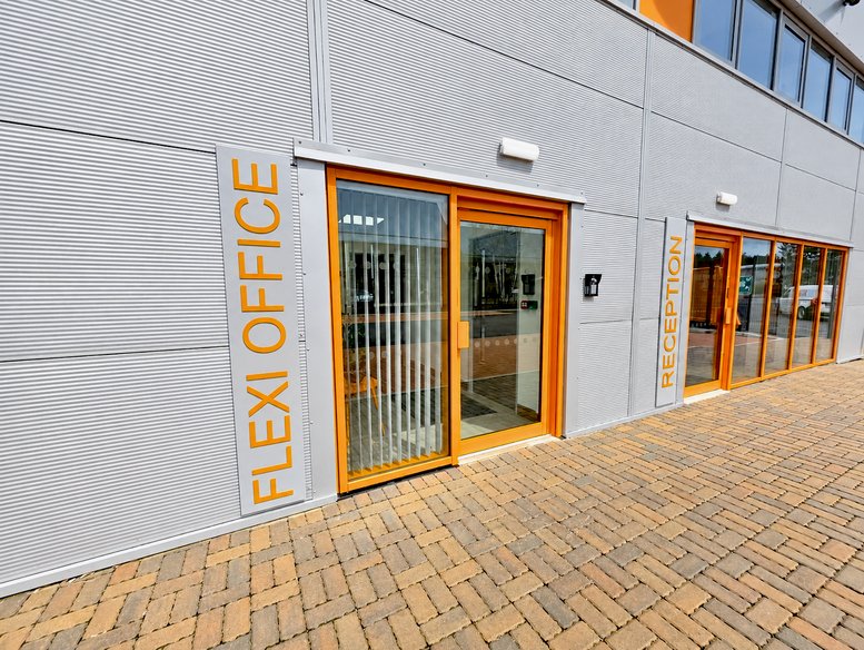 Modern exterior of Ratio Park, Fine Point Way with glass entry doors and orange accents.