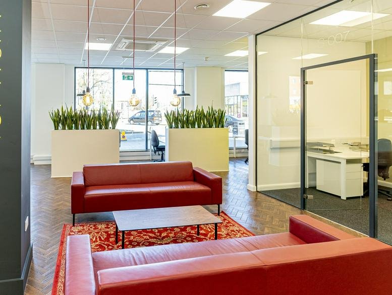 Spacious reception lounge at Regal Court Business Centre, 42, 44 High Street with red sofas and parquet flooring.