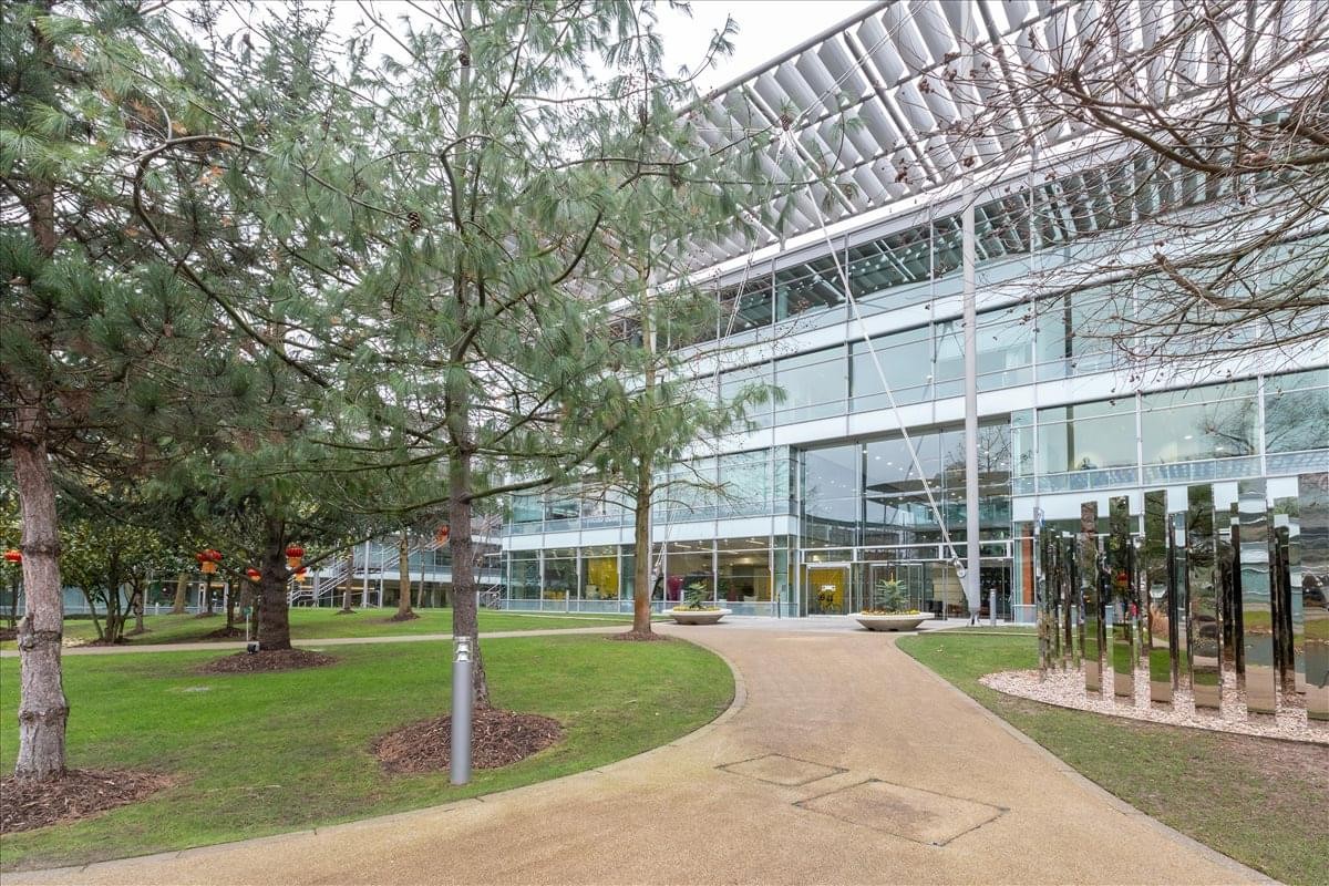 Modern glass exterior of Regus House, Chiswick Park with surrounding trees and walkway.