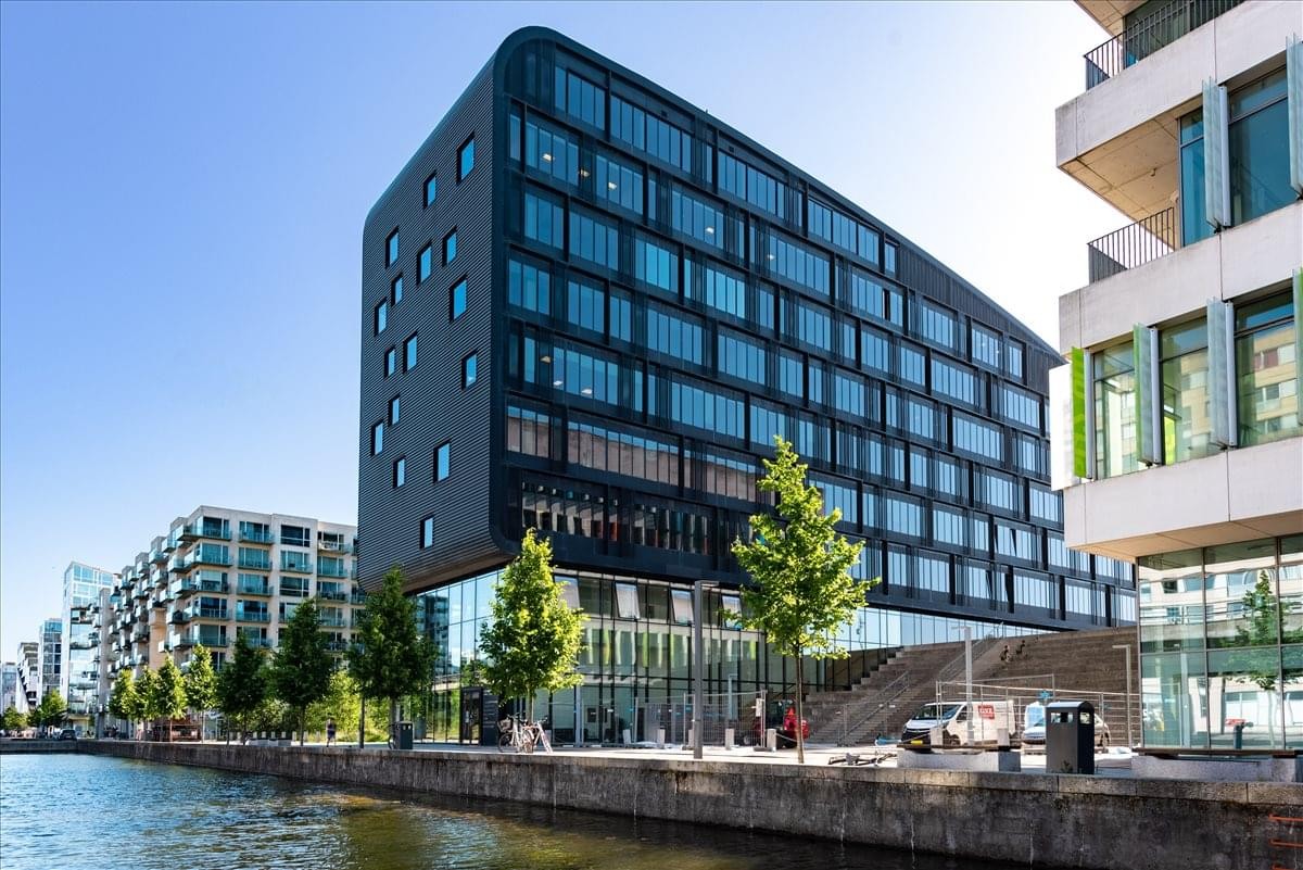 Modern black exterior of the Ørestads Boulevard 73 building alongside a canal.