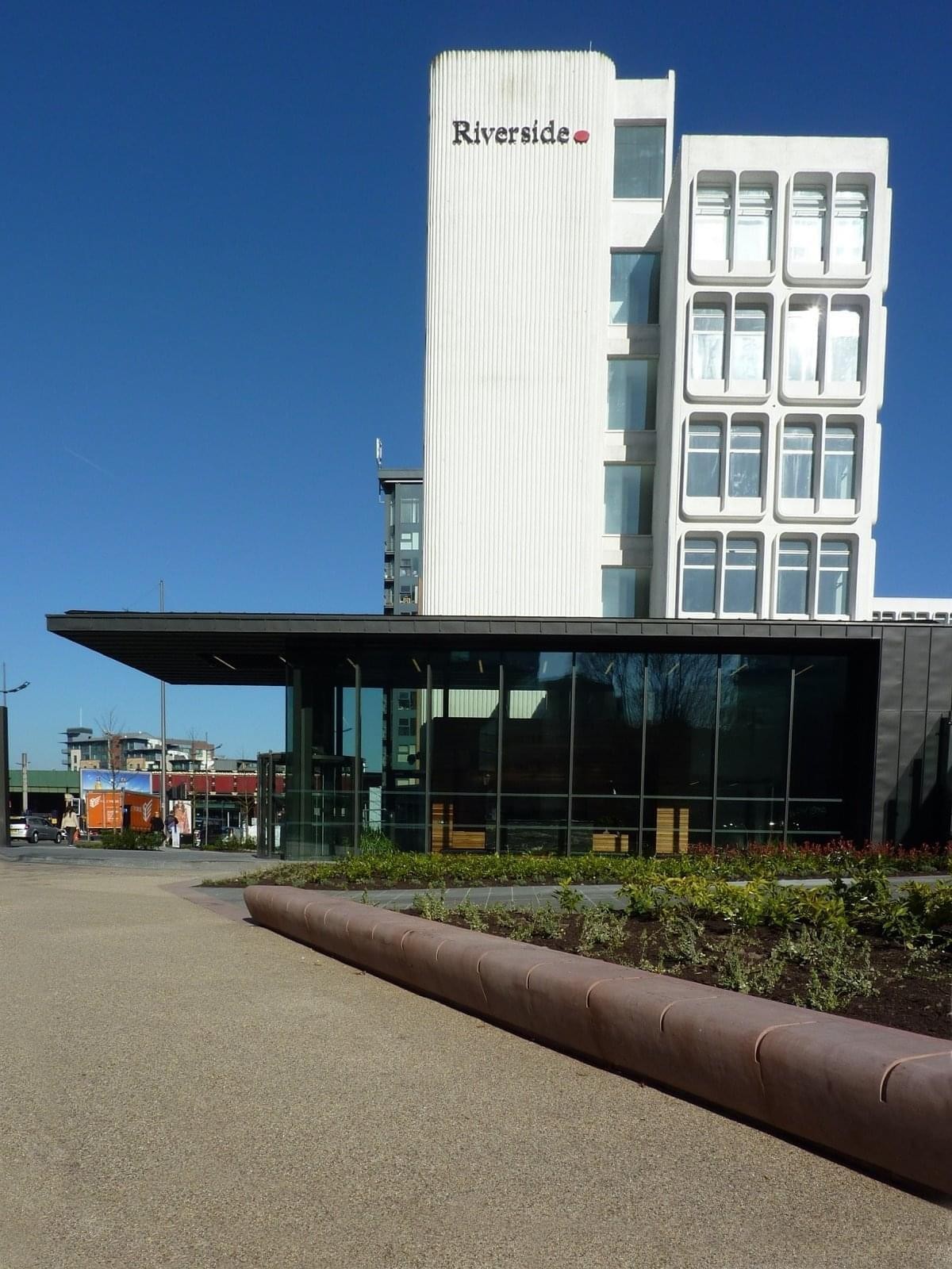The modern white facade of Riverside, New Bailey Street, Manchester against a clear blue sky.