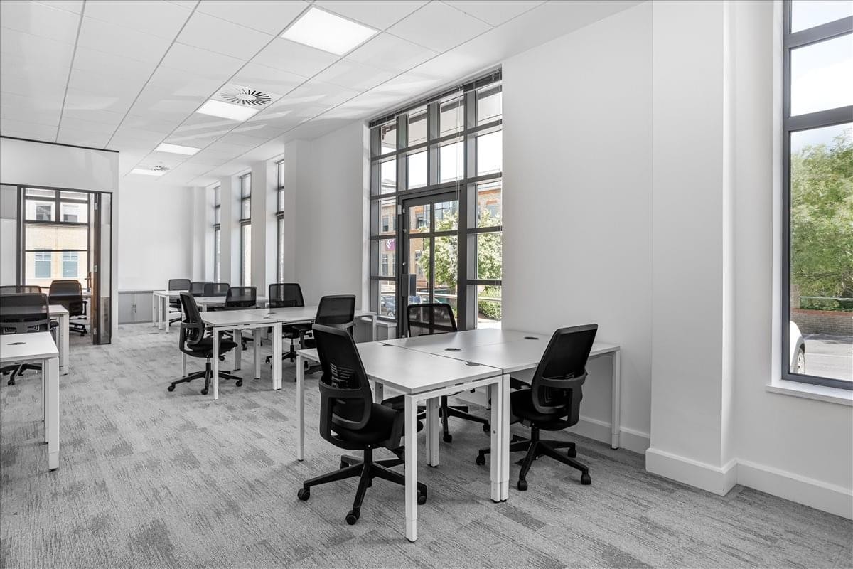 Spacious open-plan workspace at Rourke House, Watermans Business Park featuring white desks and large windows.