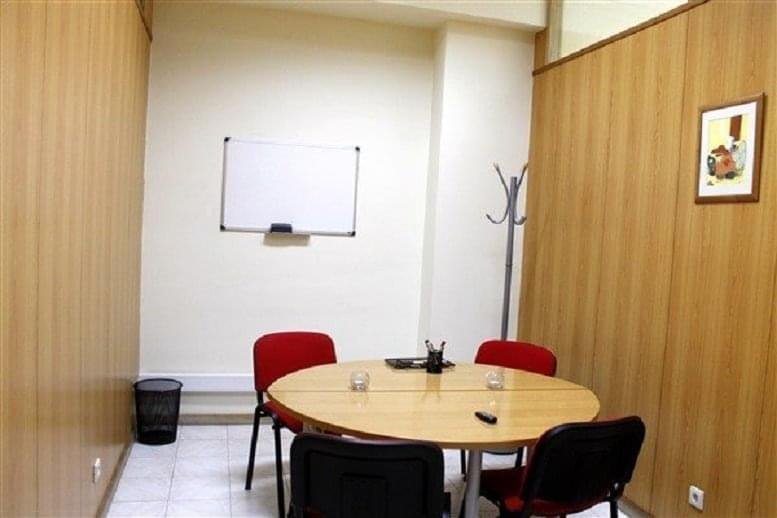 Meeting room at Rua da Boavista, 355 with a round table, red chairs, and a whiteboard.