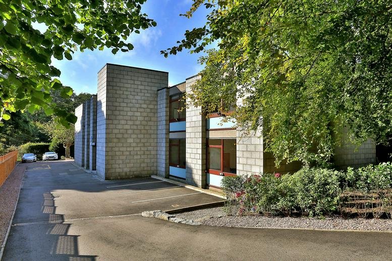 Exterior stone facade and entrance of Rubislaw Den House with surrounding greenery.