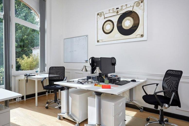 Spacious sunlit office at Rue Breydel 40 with multiple desks, modern chairs, and a large window.