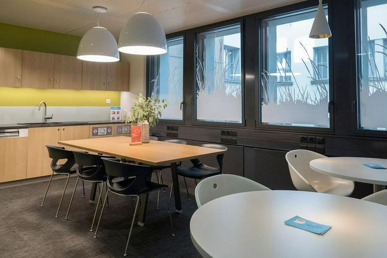 Communal break area at Rue de la Cité 1 featuring a wooden dining table and modern kitchen facilities.