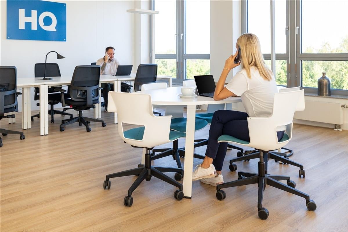 Modern coworking area with diverse seating and people working at a round table.
