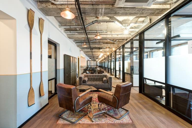 Spacious communal lounge at Salvatorplatz 3 with leather armchairs, wooden oars, and industrial ceilings.