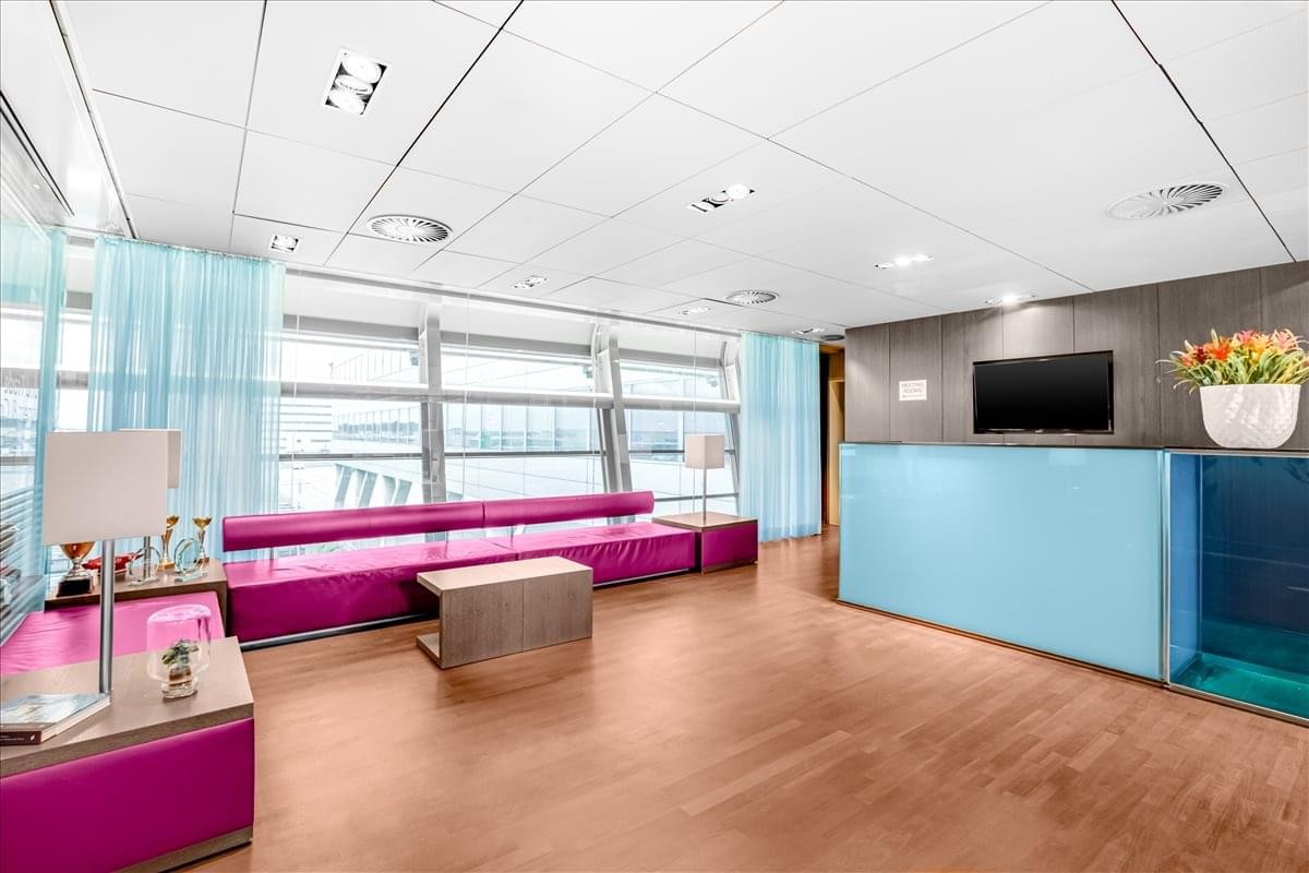 Modern reception area at Schipholboulevard 127, A3 with a long purple sofa and light blue desk.