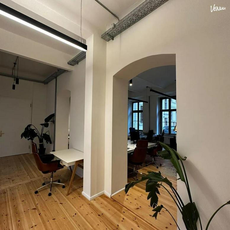 View through an arched doorway into a bright workspace with natural wood flooring.