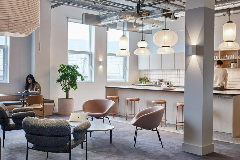 Bright breakout space with a kitchen island, bar stools, and various white pendant lamps.