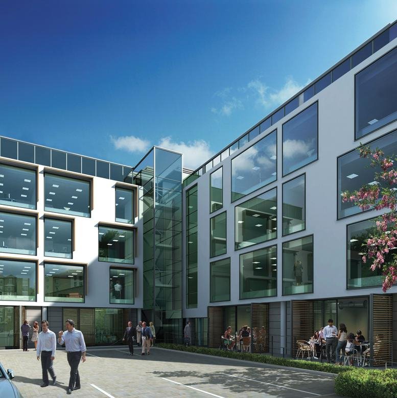 Modern exterior of the ScreenWorks building with a glass elevator shaft and outdoor seating.