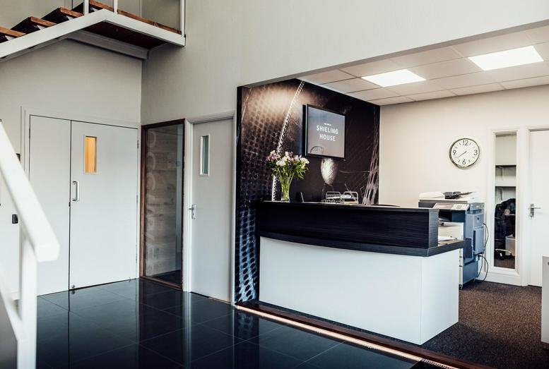 Modern reception area at Shieling House Business Centre with a sleek white desk and monochrome wall mural.