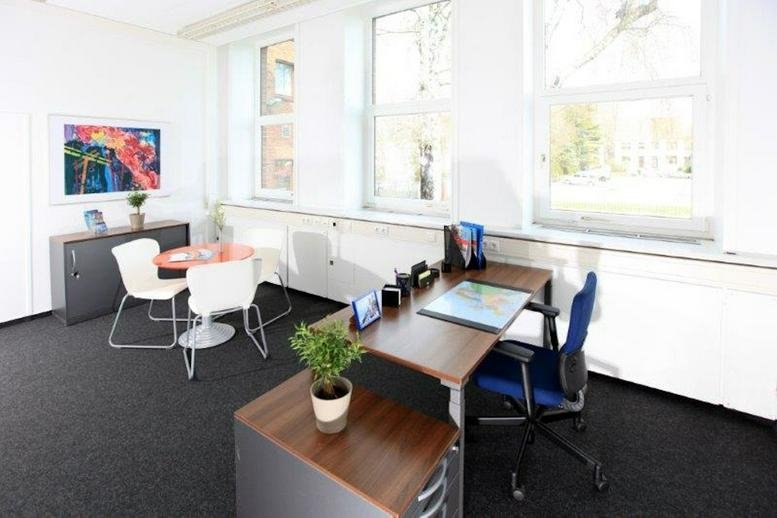 Spacious private office with dark carpeting, wooden desks, and large windows.