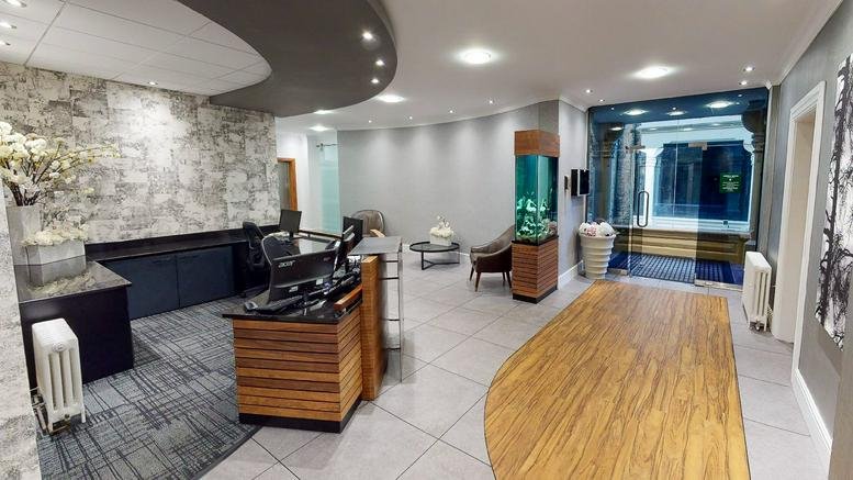Bright reception area at Sophia House with wood-paneled desk, stone feature wall, and floral arrangement.