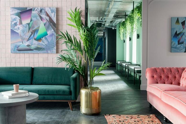 Spacious communal lounge at SouthPoint, Harmony Row featuring a green velvet sofa and pink tufted couch.