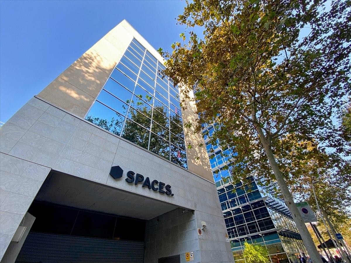 Modern glass and stone exterior of the Spaces 22 Arroba building in Barcelona.