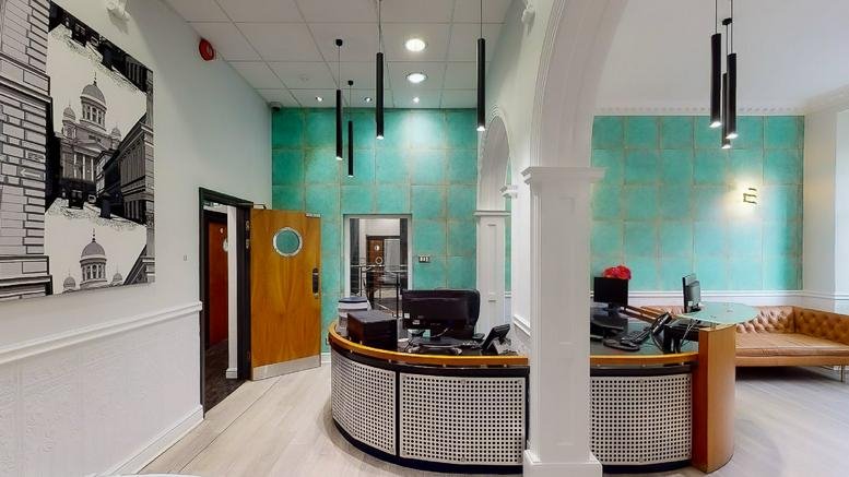 Vibrant reception area at St Brandon's House with teal feature walls and a curved front desk.