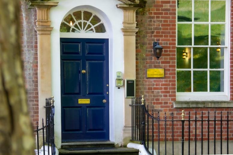 Front entrance of St Brandon's House, 29 Great George Street featuring a classic blue door and brick facade.