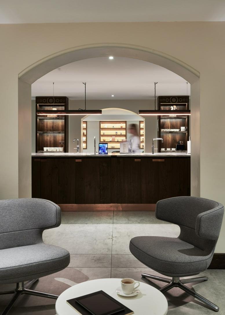 Spacious communal lounge at St Clements House, 27 Clements Lane, Central London with an arched view of a breakout bar.