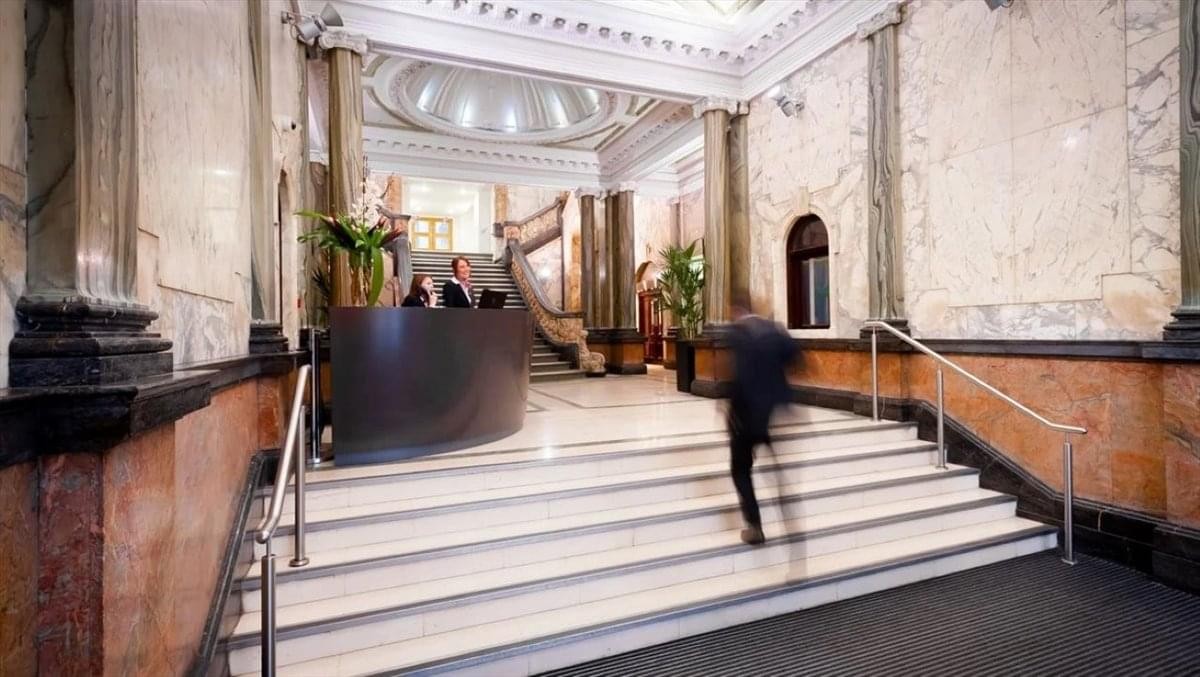 Grand marble lobby with a curved reception desk and a majestic staircase.
