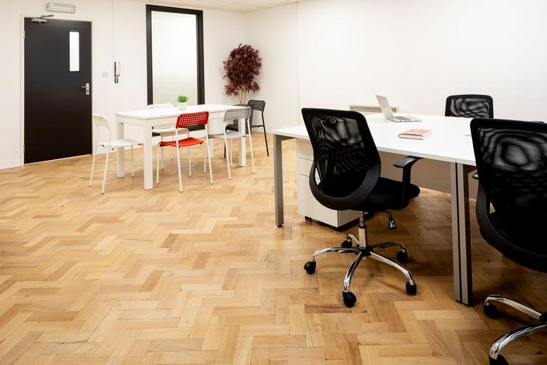 Spacious open-plan office with parquet flooring and several workstations at Steward House.