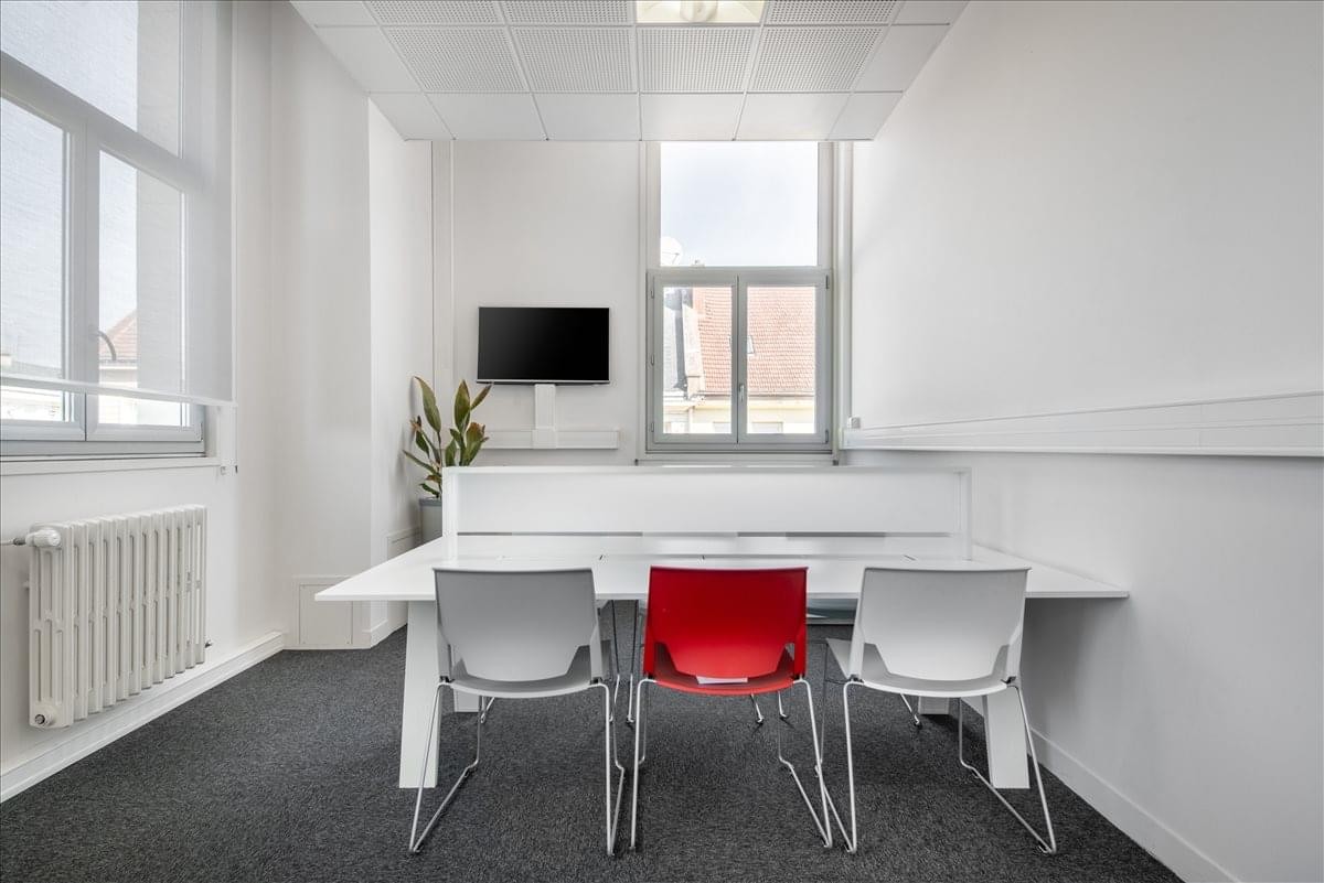 A modern workspace at Stop & Work Beauvais, Espace Galilée with white and red chairs and a wall-mounted TV.