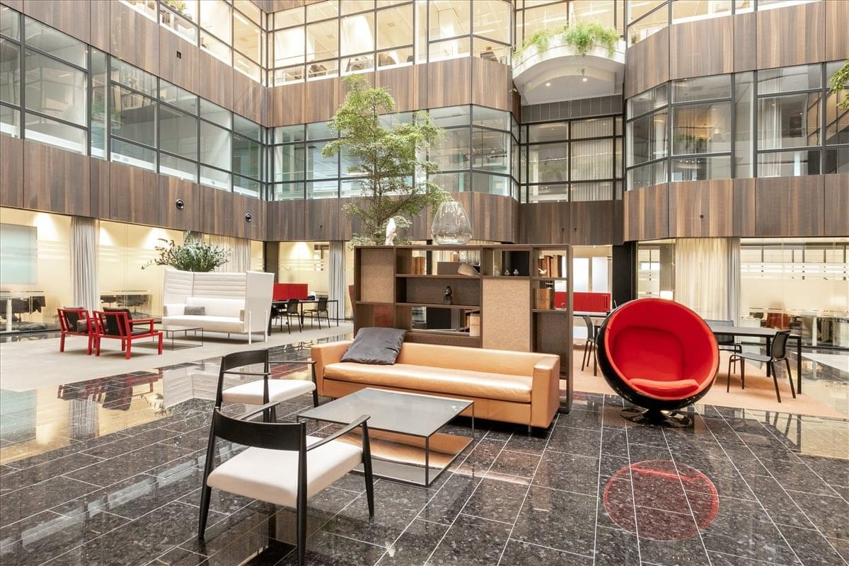 Spacious multi-story building atrium with an indoor garden and a variety of contemporary lounge seating.