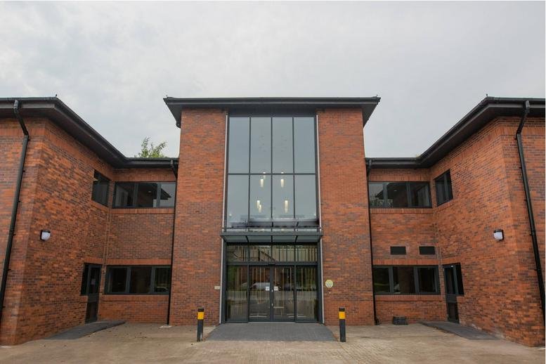 Exterior brick facade and glass entrance at Altrincham Business Park, Stuart Road, Trafford.