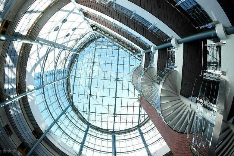 Fisheye view of a glass atrium with a spiral staircase at Tekniikantie 12 and 14; Vaisalantie 2-8.