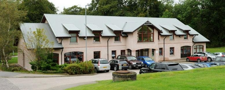 Exterior view of the multi-gabled, two-story Thainstone Business Centre with a large parking lot.