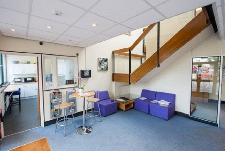 Spacious lobby area at The Canterbury Business Centre featuring purple seating and a wooden staircase.