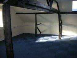 Open-plan attic workspace at The Courtyard, Milton Road, Aylesbury, Buckinghamshire with dark wooden ceiling beams.