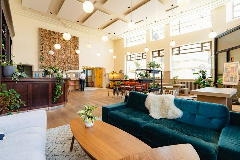 Spacious communal lounge at The Echo Building with high ceilings, velvet sofas, and a classic wood reception desk.