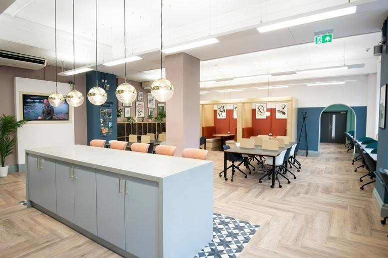 Spacious coworking area at The Leeming Building, Ludgate Hill with a large kitchen island and globe pendant lights.
