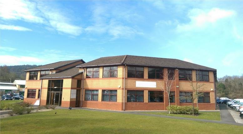 The brick and glass exterior of The Octagon, Caerphilly Business Park under a bright blue sky.