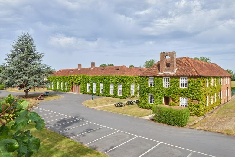 Wide exterior view of the historic red brick building at The Officers’ Mess with manicured lawns.