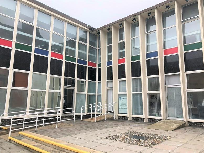 Exterior facade of The Old Library, St Faiths Street with modern glass windows and colorful panels.