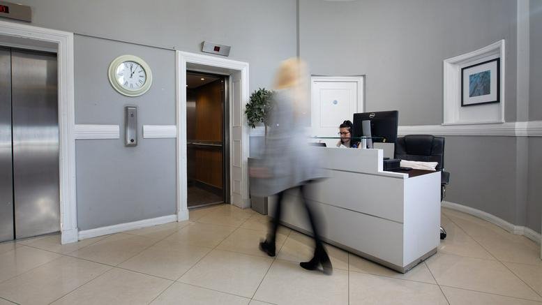Bright reception area with a white desk and elevators at The Old Town Hall, 4 Queens Road.