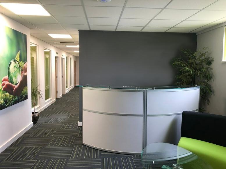 Modern reception area at The Oxford Eco Centre, Roger House with a curved white desk and grey feature wall.