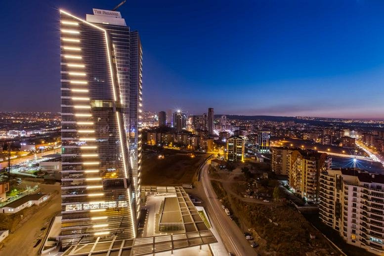 Exterior night view of the illuminated glass facade of The Paragon Tower in Ankara.