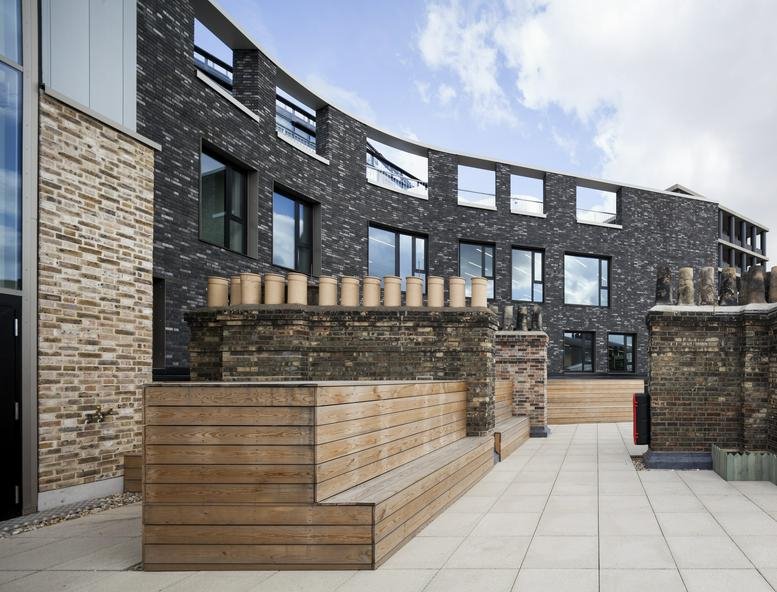 The brick and glass exterior of The Stanley Building featuring a curved facade and outdoor terrace seating.