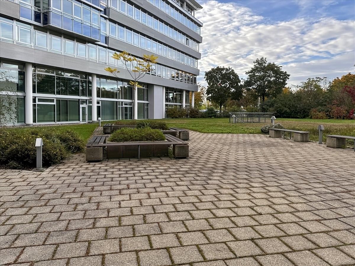 Exterior building view of the modern glass-fronted Theodor-Heuss-Anlage 12 with a paved courtyard.