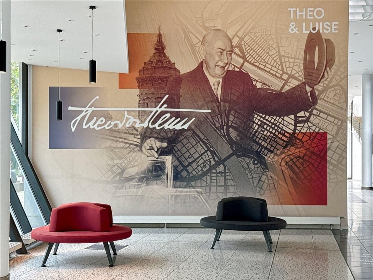 Lobby area at Theodor-Heuss-Anlage 12 featuring a large illustrative wall mural and modern seating.