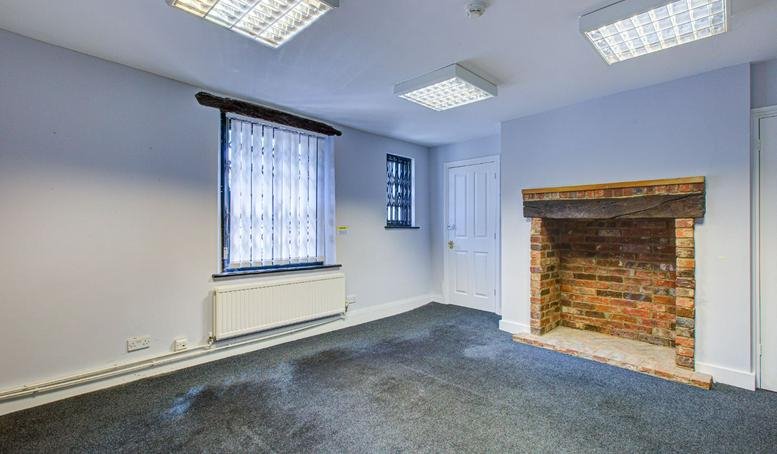Spacious private office at Three Gables, Corner Hall featuring a brick fireplace and large windows.