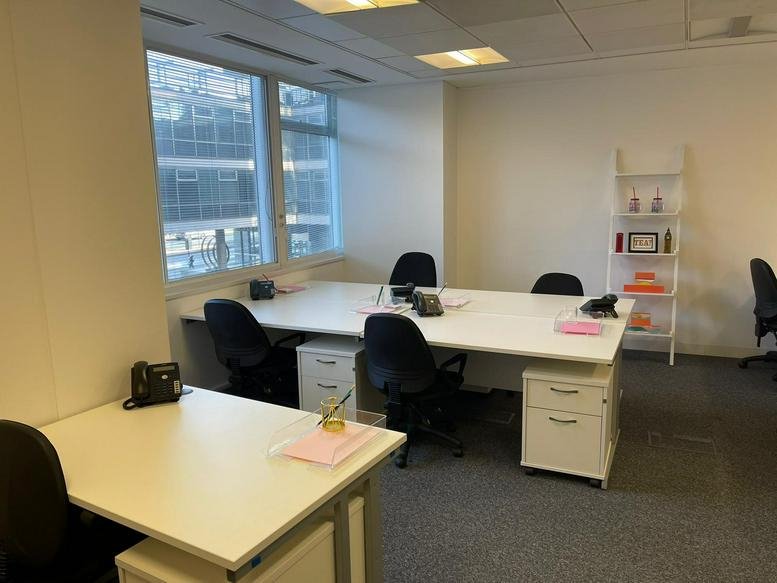 Private office suite with white desks, grey chairs, and a window view.