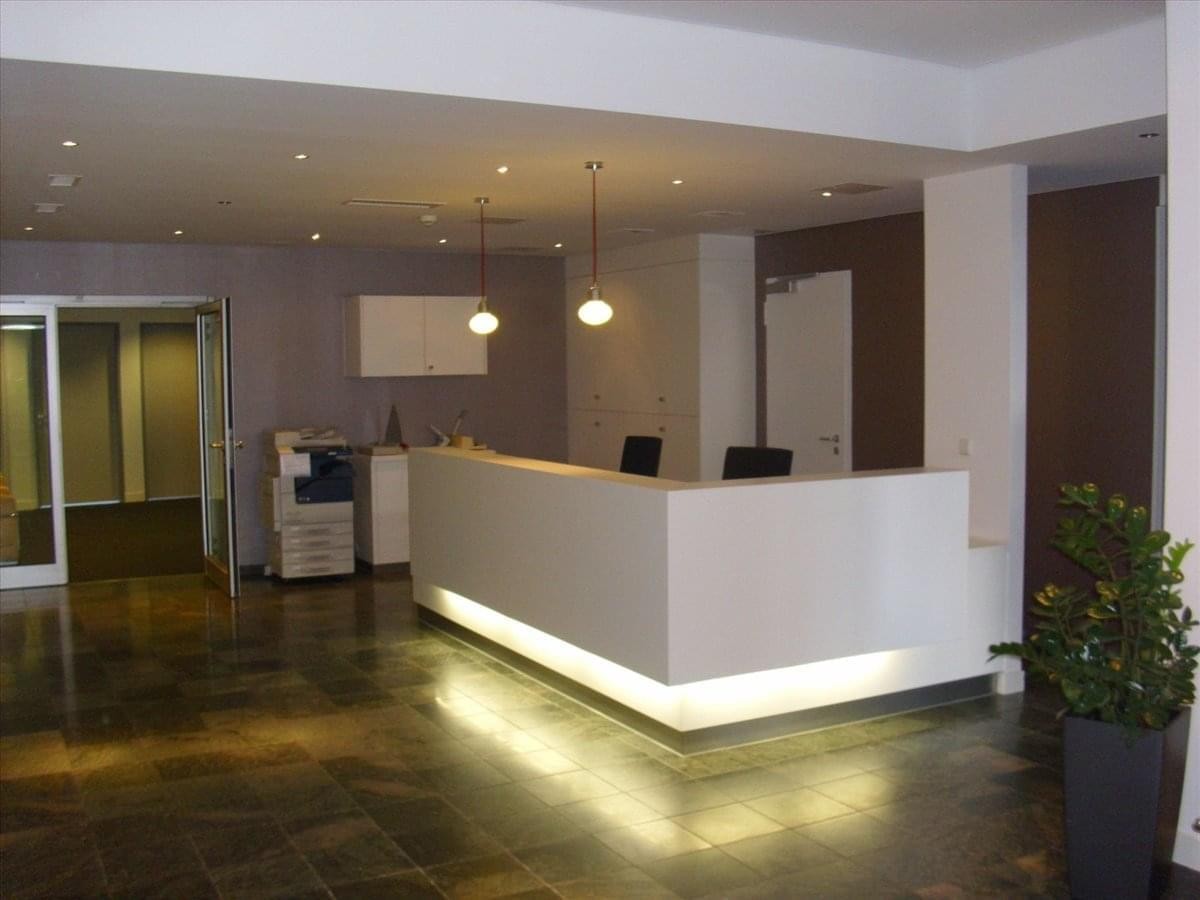 Bright, modern reception area at Torgauer Straße 231-233 with a backlit desk and warm lighting.