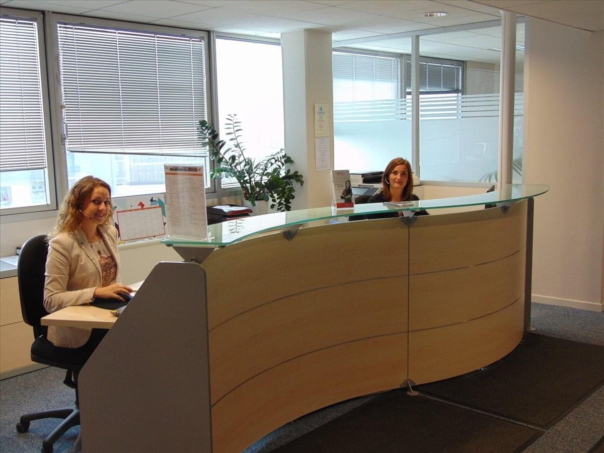 Bright reception area at Toulouse Compans, 1 Esplanade Compans Caffarelli, with a curved wood and glass desk.